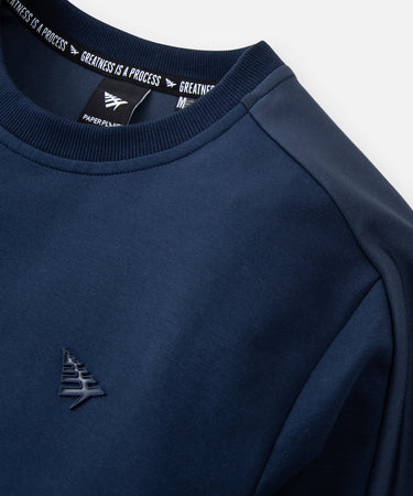 CUSTOM_ALT_TEXT: Ribbed neck, pieced shoulder, and glossy silicone Plane chest icon on Paper Planes Chromatic Crewneck Sweatshirt color Naval Academy.