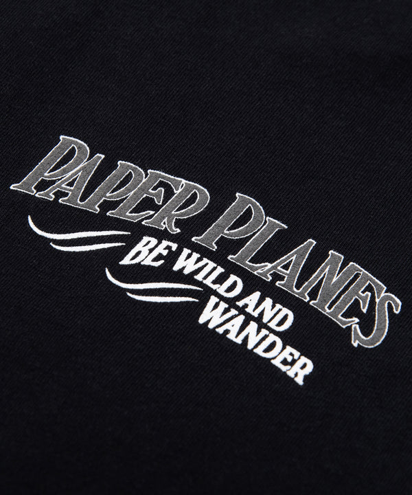 CUSTOM_ALT_TEXT: Print closeup on Paper Planes Be Wild and Wander Tee, color Black.