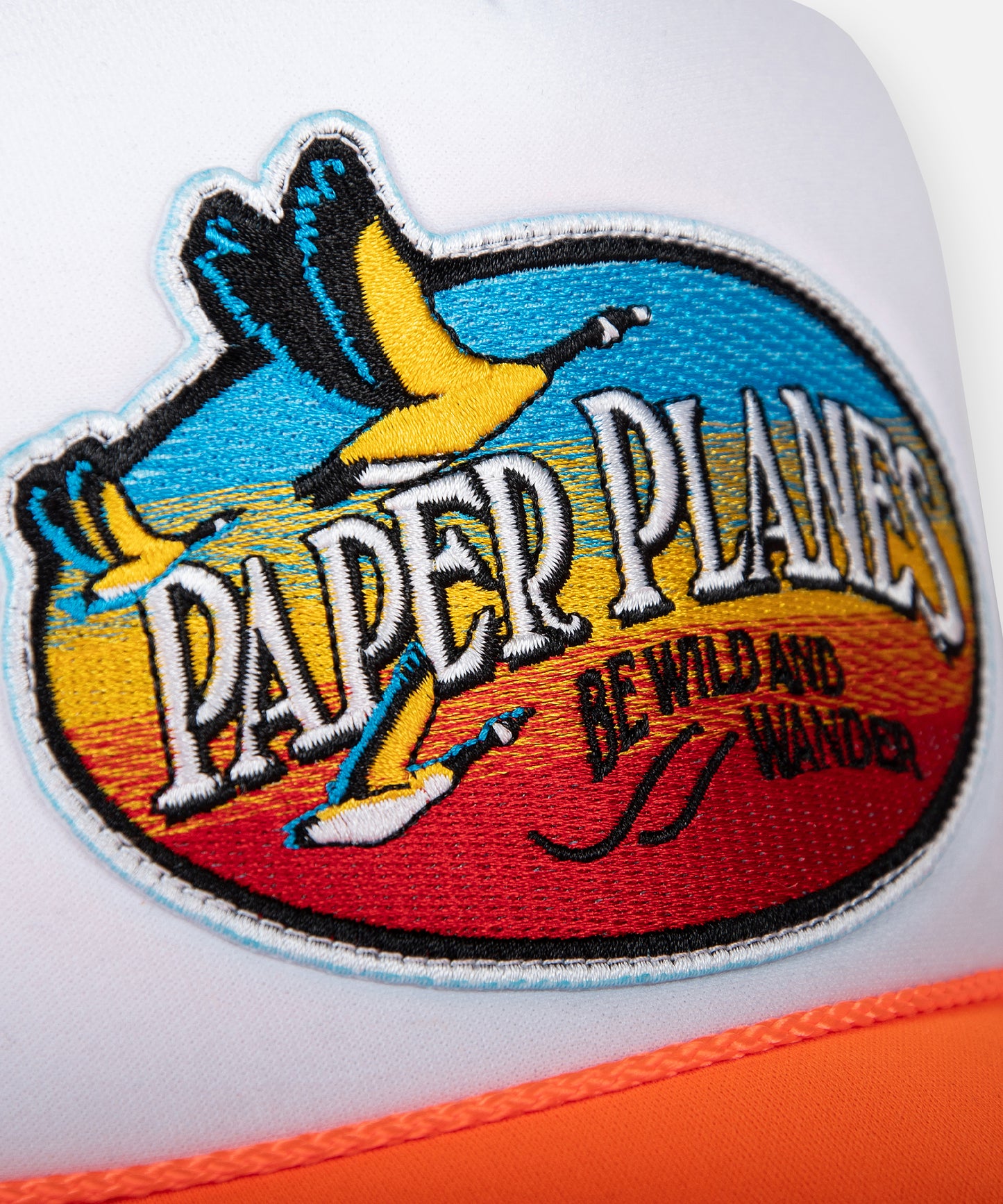 CUSTOM_ALT_TEXT: Embroidery patch on Paper Planes Be Wild and Wander Trucker.
