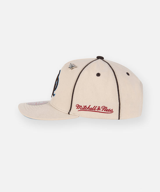 CUSTOM_ALT_TEXT: Mitchell & Ness embroidery on Paper Planes PPL A-Frame Curved Visor, color Irish Cream.