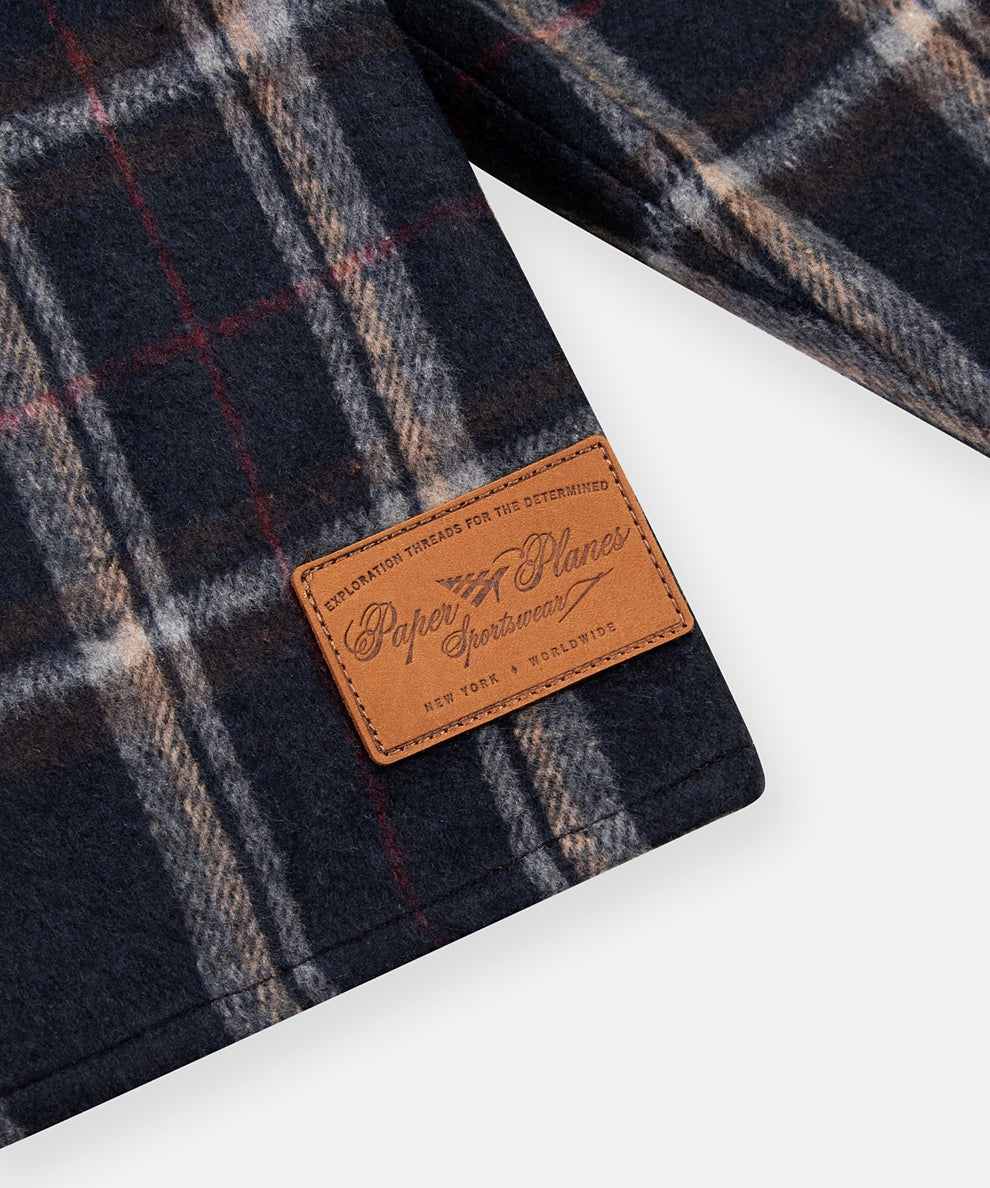 CUSTOM_ALT_TEXT: Paper Planes Sportswear debossed leather patch on Paper Planes Plaid Brushed Flannel Tunic.