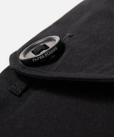 CUSTOM_ALT_TEXT: Fabric-looped oversized slot-hole logo-ed button on Paper Planes Cotton Touch Explorer’s Cargo Pant, color Black.