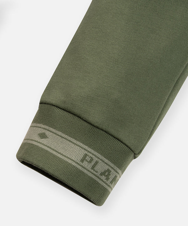 CUSTOM_ALT_TEXT: Tonal jacquard flat knit rib cuff on Paper Planes Logo Jacquard Pant, color Bronze Green.