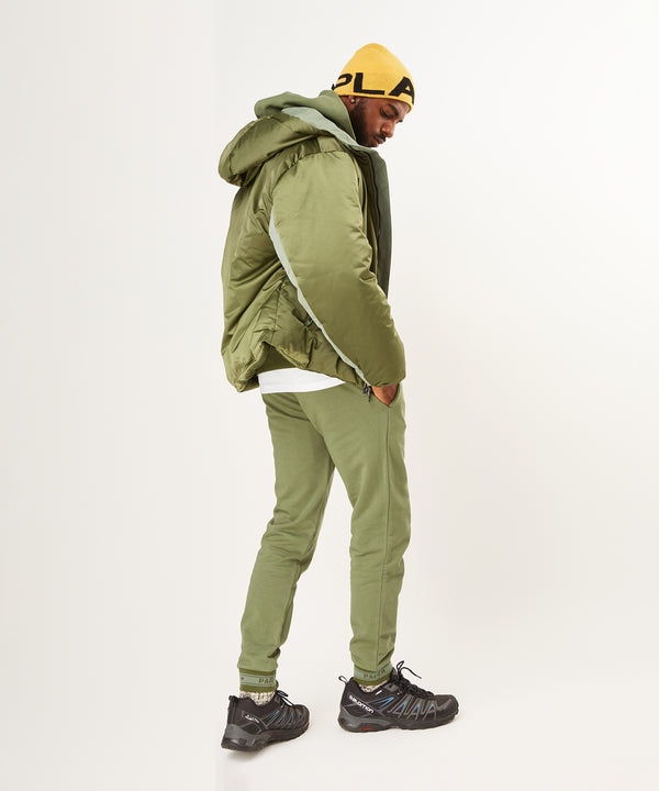 CUSTOM_ALT_TEXT: Side view of male model wearing Paper Planes Puffer Jacket, color OD Green.