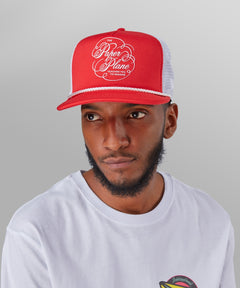 Male model wearing Paper Planes Script Trucker Hat color Coral Red.
