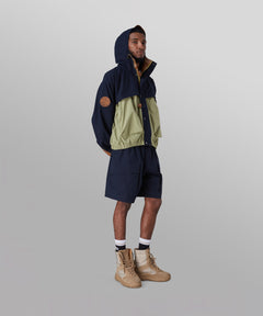 Male model wearing Paper Planes Super Cargo Short color Indigo with Lovers & Friends Hooded Ripstop Jacket.